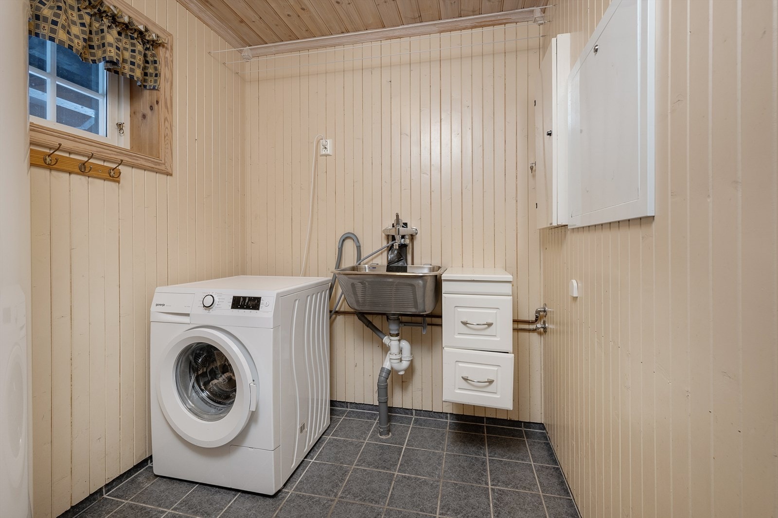 Separat vaskerom med flislagt gulv, utslagsvask og opplegg for vaskemaskin. Galleribilde