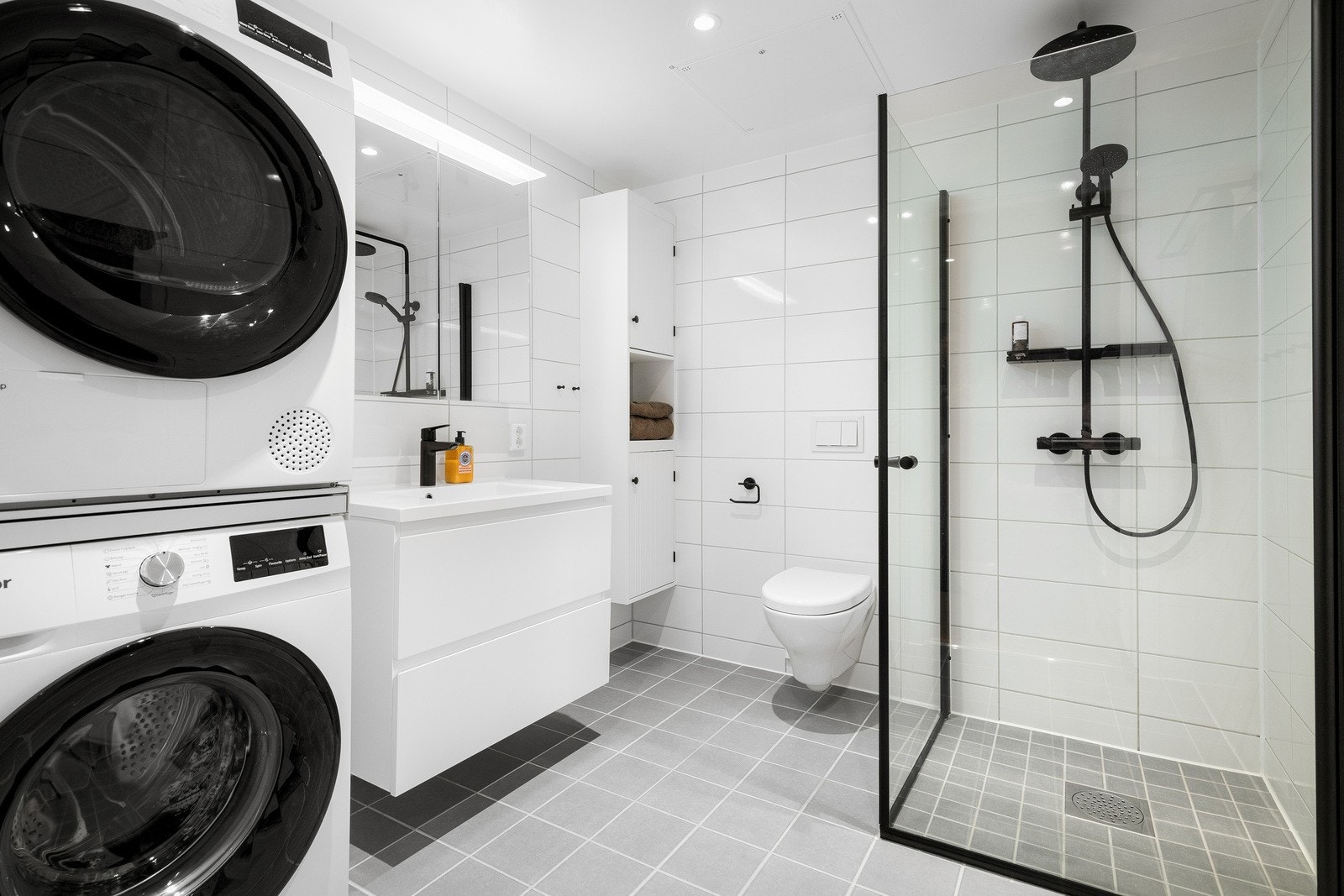 Baderommet er stilrent med plass til vaskemaskin og tørketrommel som medfølger boligen ved salg. Galleribilde