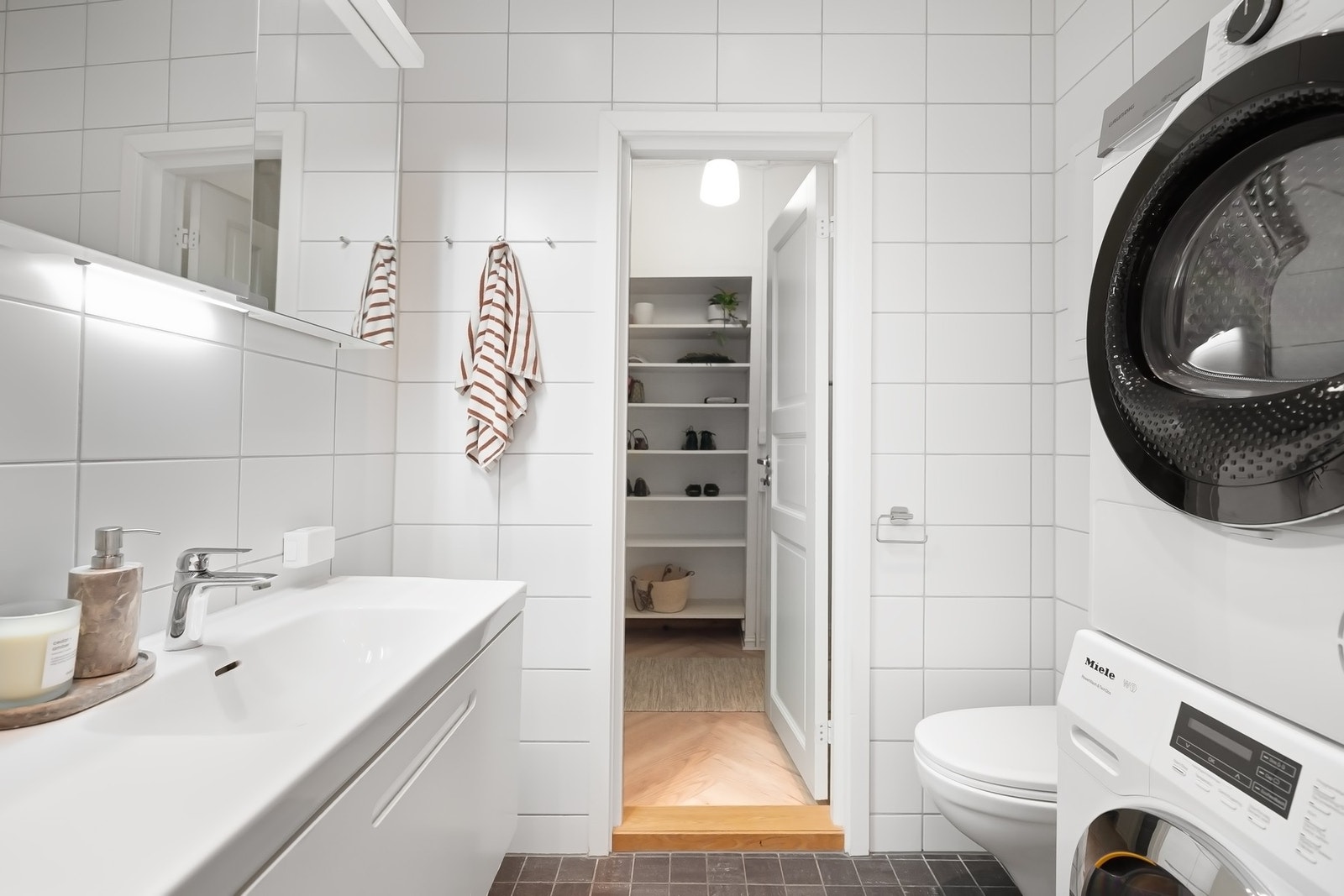 Badet har flislagte vegger og gulv med varmekabler, og er innredet med baderomsinnredning med speil, badekar med dusj og opplegg for vaskemaskin. Galleribilde