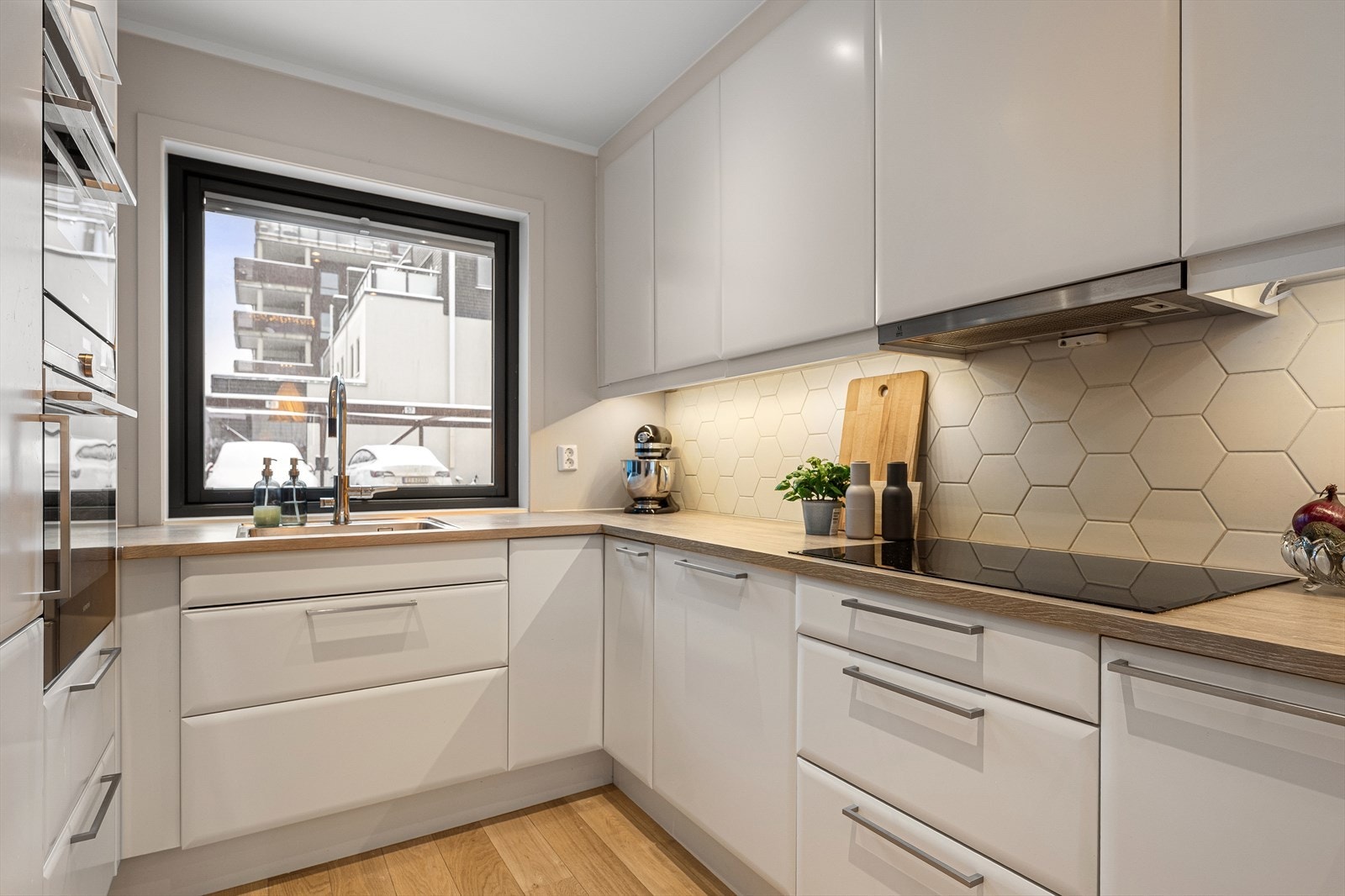 Flott og moderne kjøkken med hvite, slette fronter og nedfelt vaskekum i benkeplate av laminat. Galleribilde