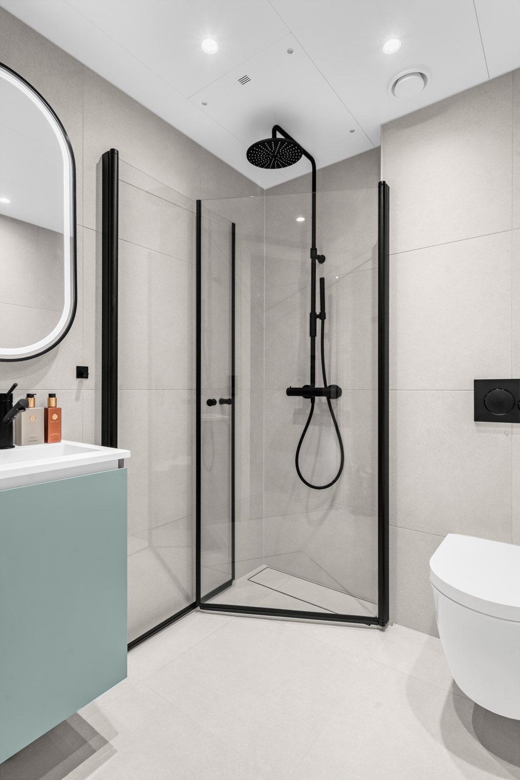 Delikat flislagt bad II med adkomst fra gangen. Badet inneholder servant, speil, dusjhjørne med glassdører, Tapwell armatur med regndusj og hånddusj, Tile Insert linjesluk og vegghengt wc med innebygget sisterne. Galleribilde