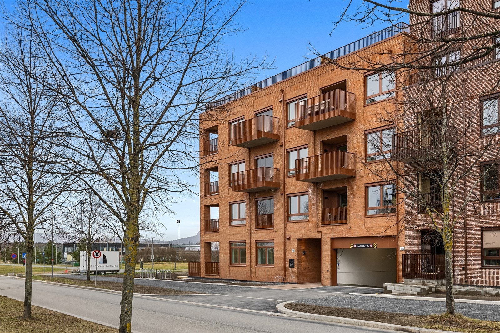 Inngang og innkjøring til garasjen fra Forneburingen. Nansenløkka 18 har en svært sentral beliggenhet på Fornebu med umiddelbar nærhet til Fornebu S, flere parker og fjorden. Galleribilde