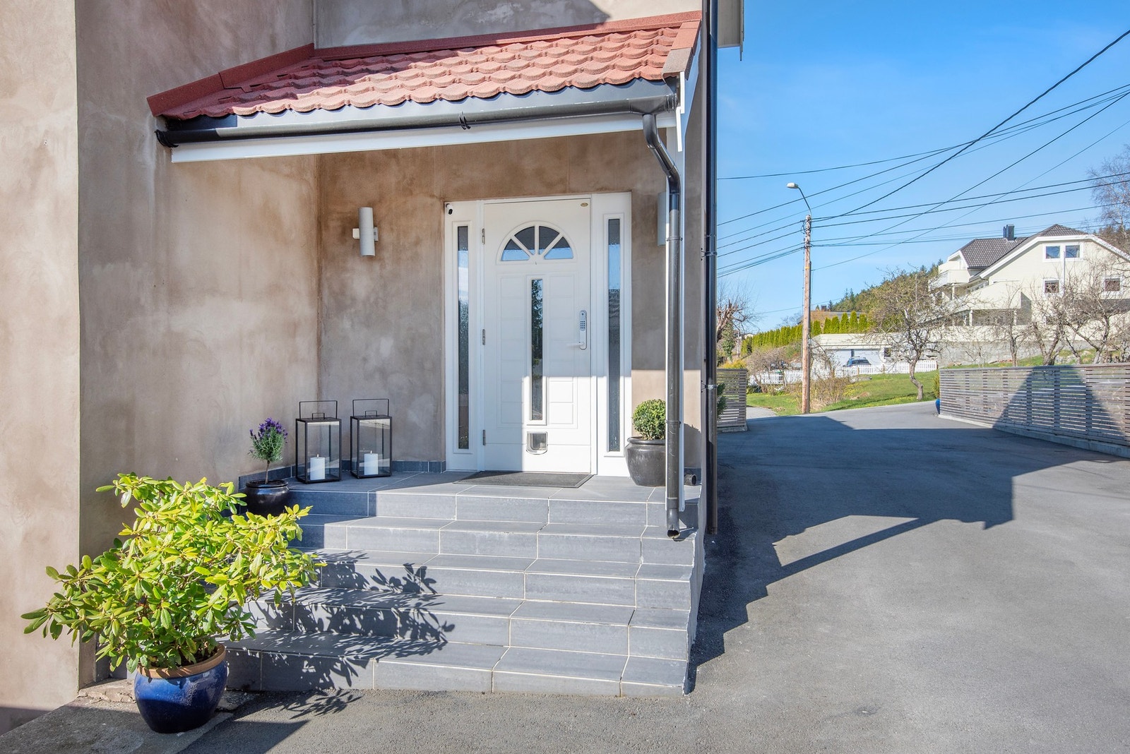Pent overbygd inngangsparti med flislagt betongtrapp. Galleribilde