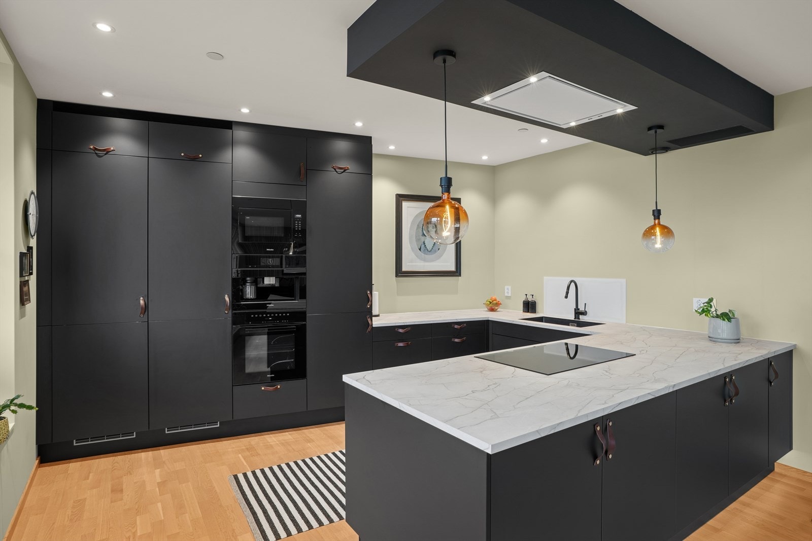 Kjøkkenet er utstyrt med en mørk, glatt kjøkkeninnredning fra 2022 med laminat benkeplate og malte flater over benken. Galleribilde