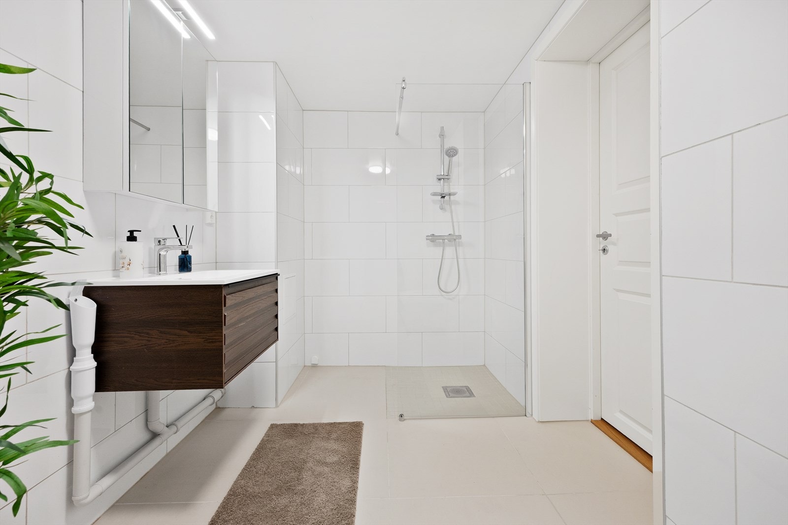 Baderommet er innredet med vegghengt toalett, servant med skuff og en dusjnisje med glassvegg. Galleribilde