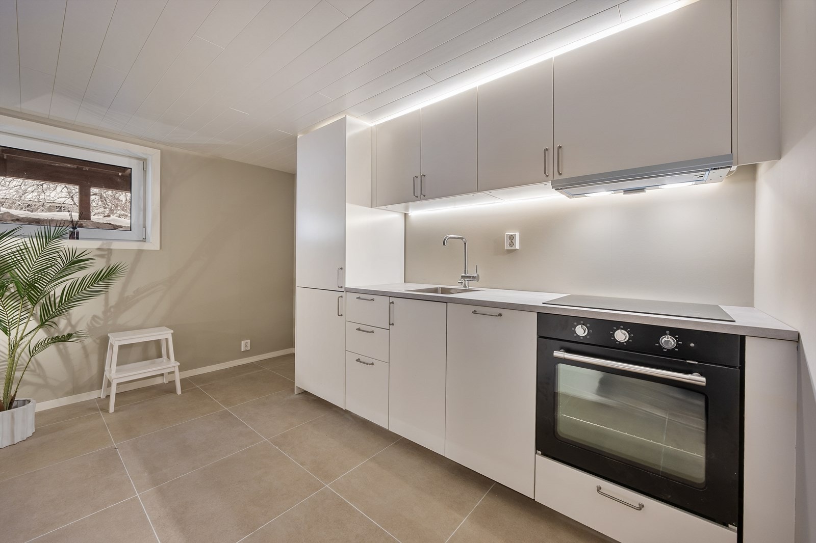 Integrerte hvitevarer som stekeovn og induksjonstopp, oppvaskmaskin og kjøleskap. Galleribilde