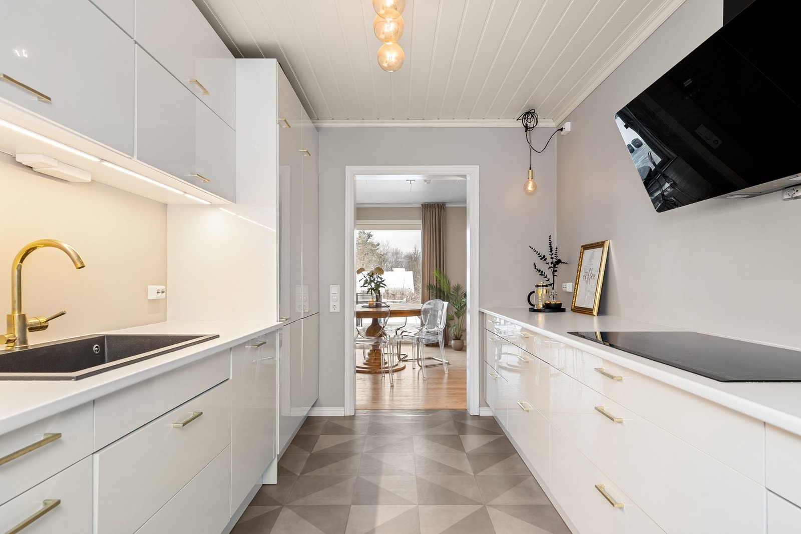 Pent kjøkken med integrerte hvitevarer og balkongdør ut til inngangspartiet som har fin morgensol Galleribilde