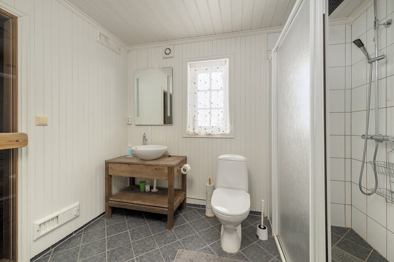 Flislagt bad med gulvvarme, dusjhjørne og servantmøbel i tre. Galleribilde