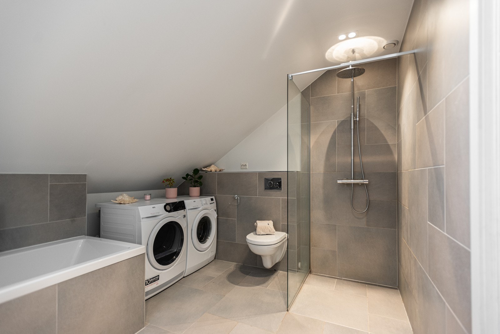 Vegggengt toalett, innmurt badekar og dusjhjørne med regnfallsdusj Galleribilde