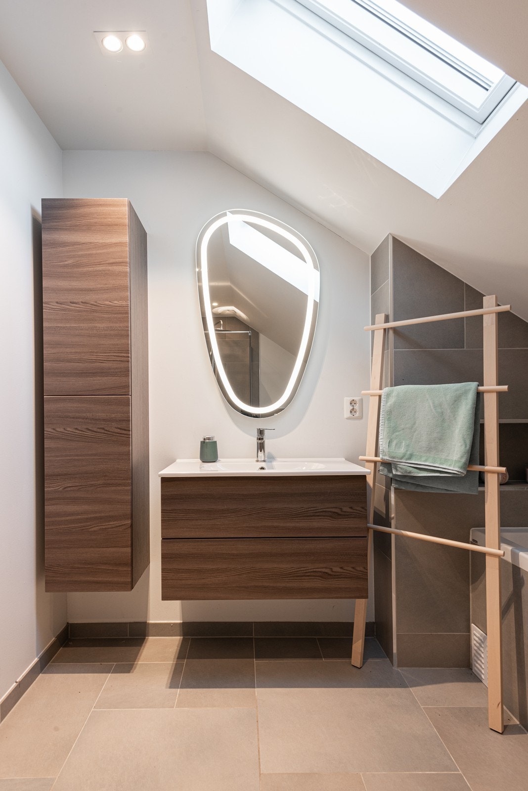 Baderomsinnredning med lysspeil og tilhørende høyskap - gode oppbevaringsmuligheter Galleribilde