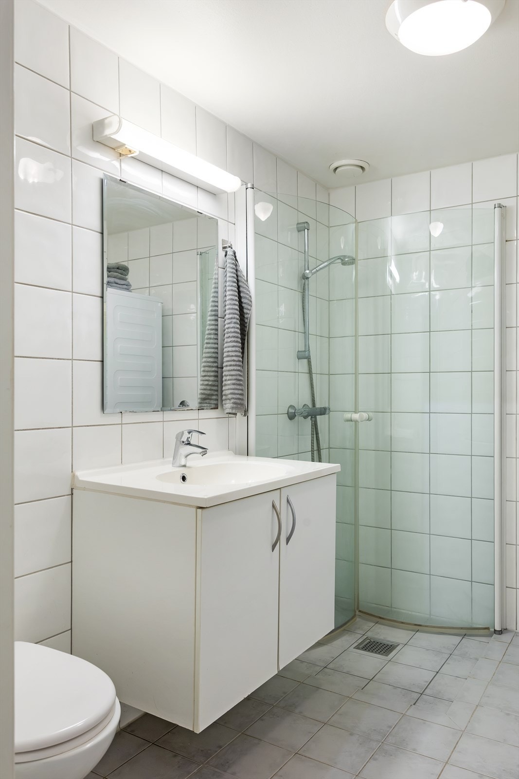 Badet er innredet med vegghengt klosett, servant med innredning og dusjhjørne med svingbare glassdører - det er opplegg for vaskemaskin! Galleribilde