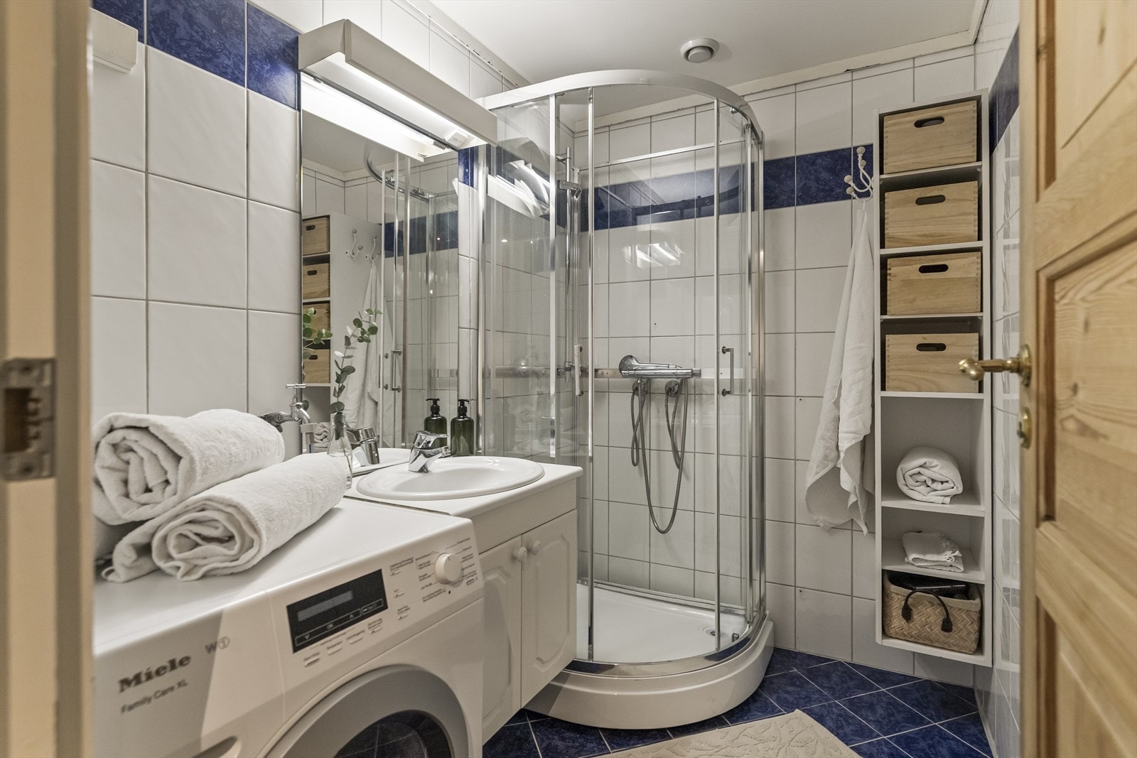 Badet er utstyrt med flislagte overflater, varmekabler i gulv, dusjkabinett og opplegg for vaskemaskin. Galleribilde