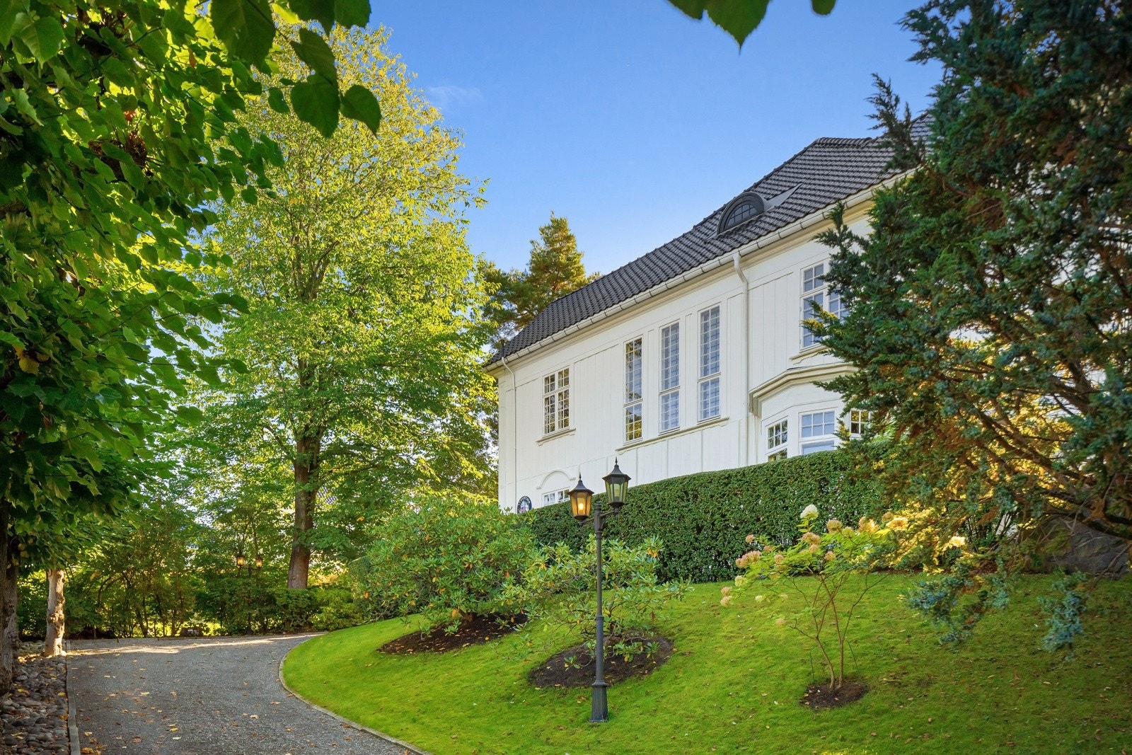 Den vakre villaen ligger flott til på tomtens høyeste punkt, og fasaden har original kledning med markante og noe dekorerte hjørnekasser. Galleribilde