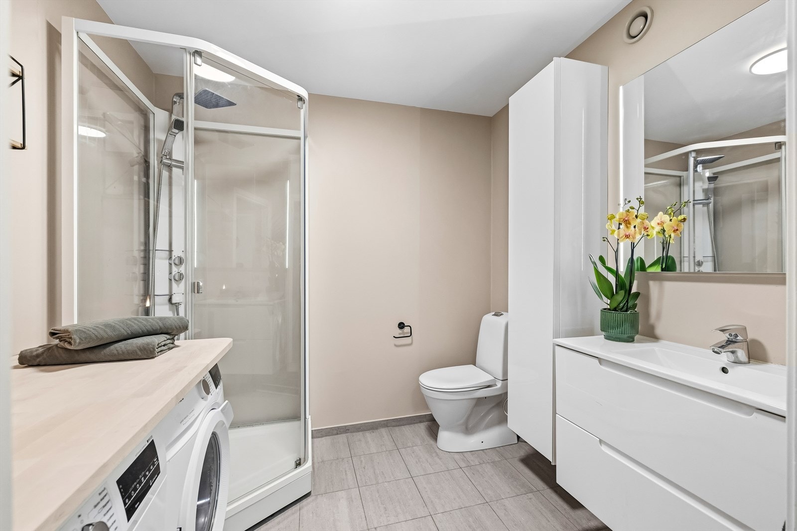 Pent og romslig bad med dusjkabinett, servant med innredning og toalett. Flislagt gulv og lyse overflater gir et tidløst og praktisk uttrykk. Galleribilde