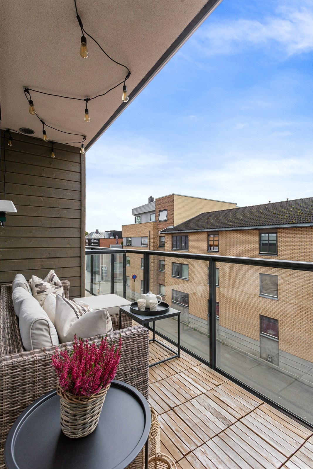 Balkong med trefliser på gulv, utvendig belysning og strømuttak Galleribilde