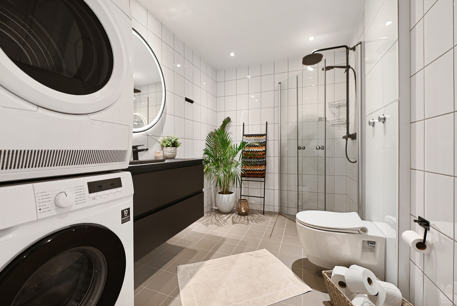 Badet er innredet med dusjhjørne, servant, speil, vegghengt wc og opplegg for vaskemaskin.
Servantskap og blandebatteri, og dusjgarnityr er fra 2025. Galleribilde