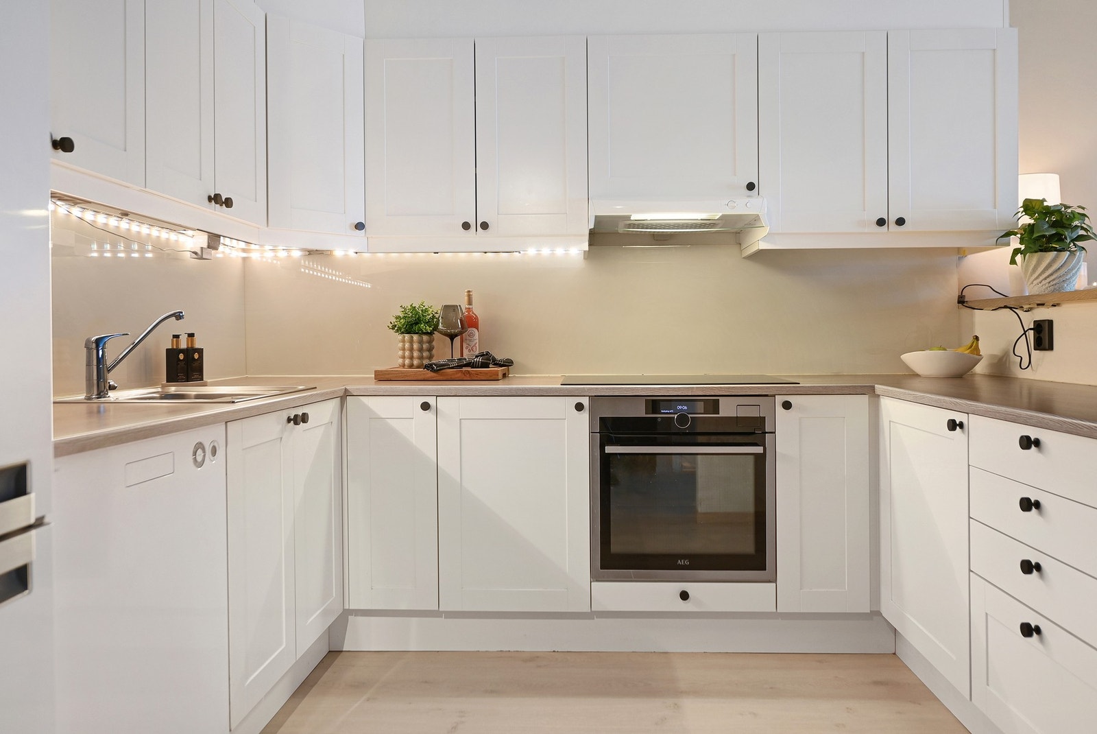 Det er gode arbeidsflater på en laminat benkeplate i hestesko med barløsning mot stuen. Det er byttet dørhåndtak og knotter på kjøkkenskapene. Galleribilde