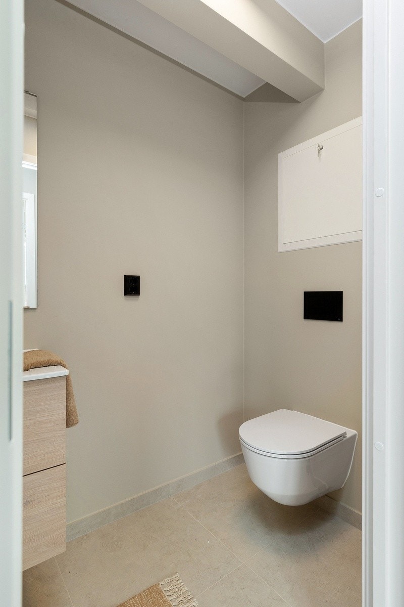 Praktisk ekstra toalettrom med flis på gulv og høy standard. Toalett og servant. Galleribilde