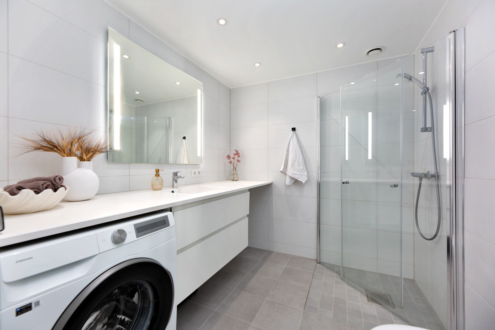 Stilrent baderom med gulvvarme og downlights. Det er opplegg for vaskemaskin og tørketrommel. Galleribilde