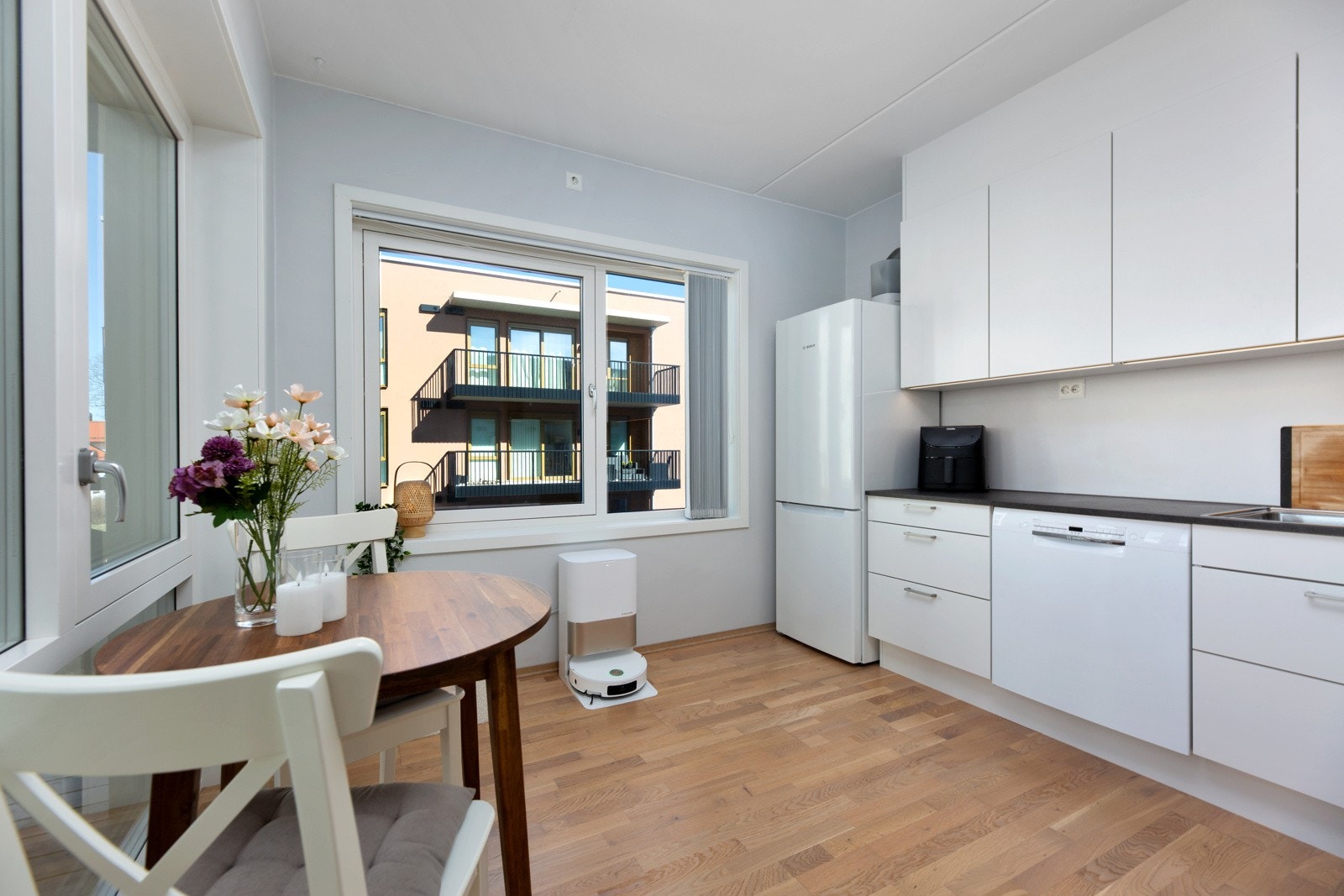 Pent kjøkken fra byggeår med slette, lyse fronter, laminerte benkeplater og ellers godt med skap- og benkeplass. Galleribilde