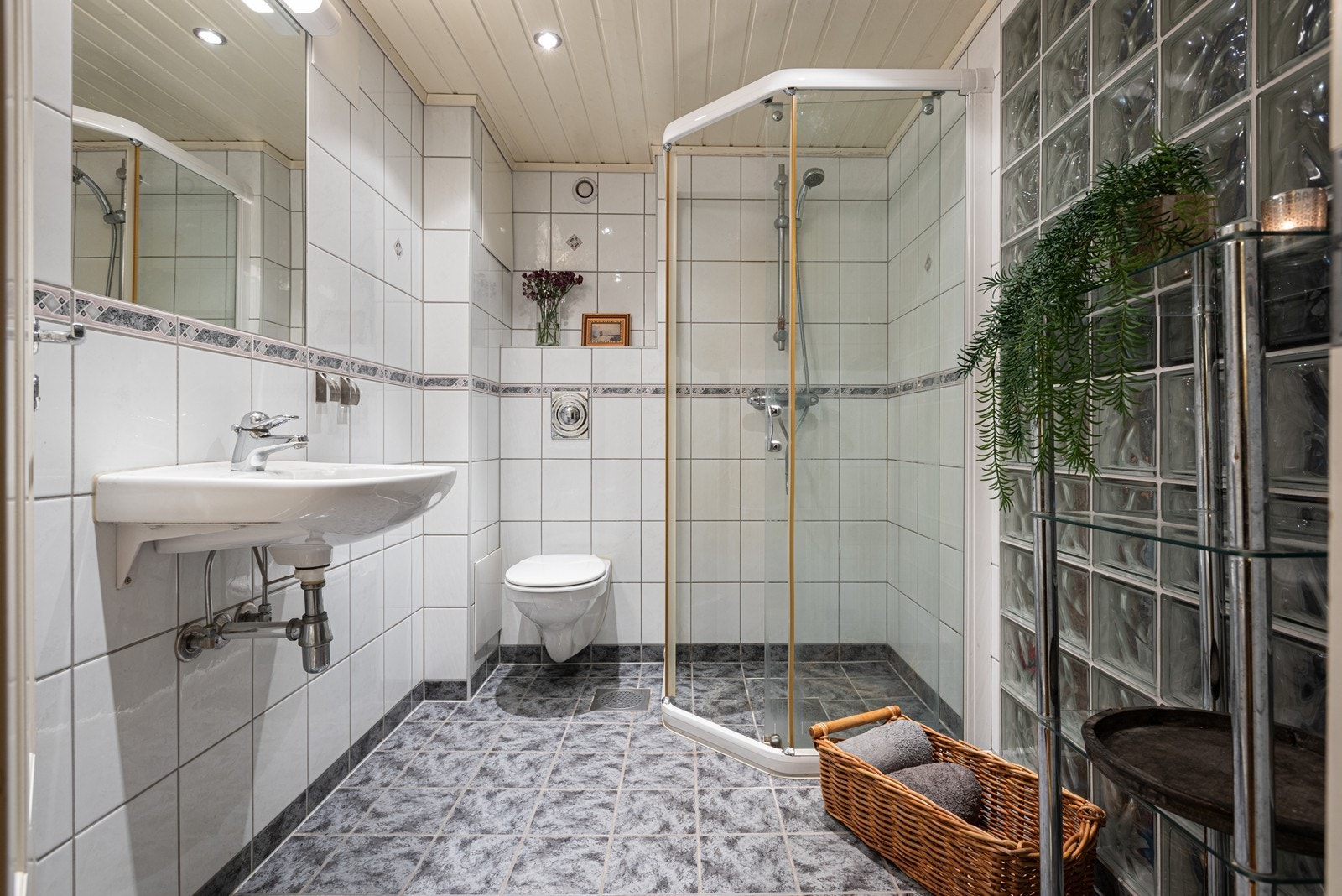 Flislagt bad med dusjhjørne, behagelig gulvvarme og dimbar belysning. (Badet er byggemeldt som bod. For at det skal kunne kalles bad i byggemeldte plantegninger må det søkes om bruksendring). Galleribilde