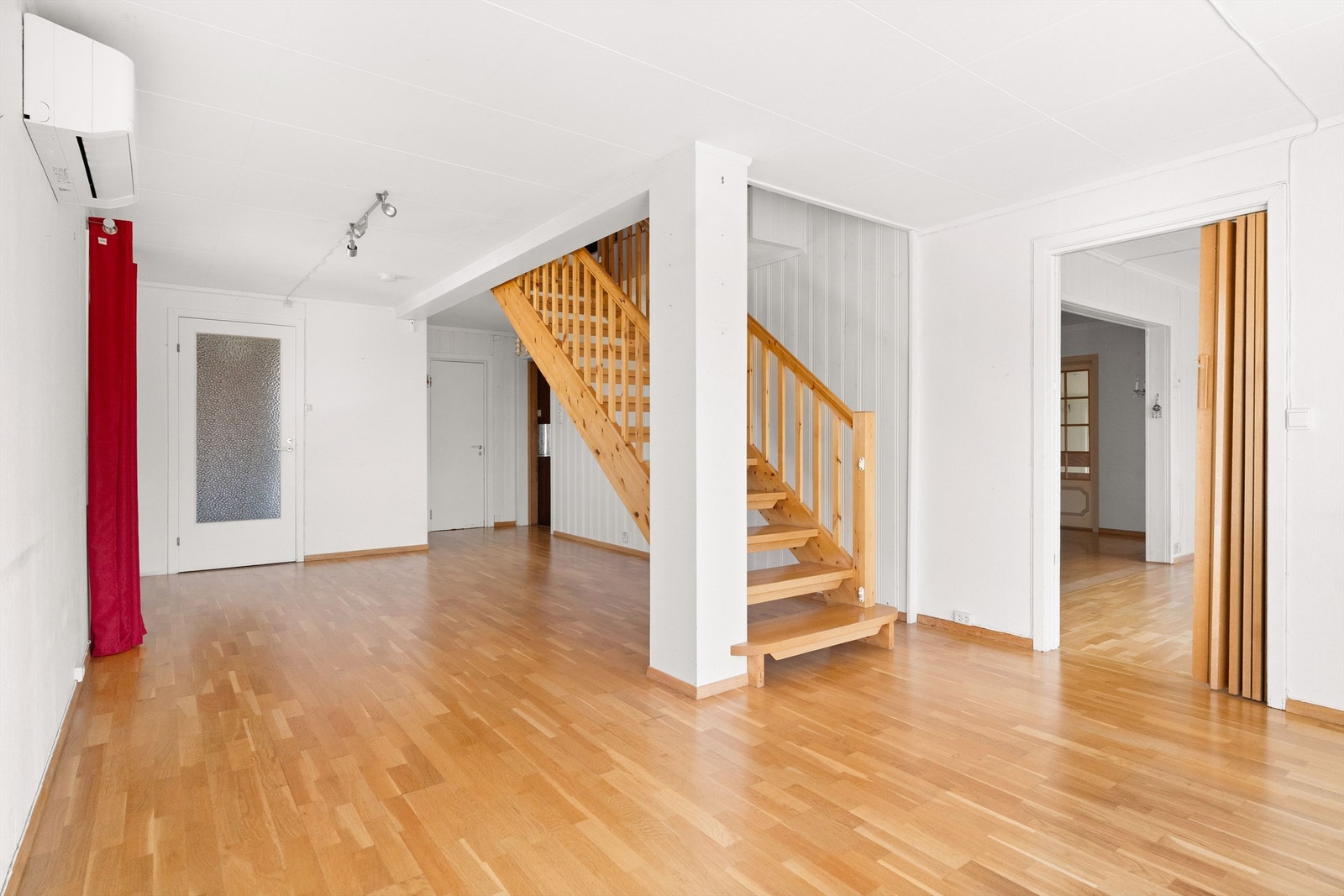 Stue i 1.etg. med varmepumpe. Midt i bilde er trapp til 2.etg.og inngang til kjøkken og bad Galleribilde