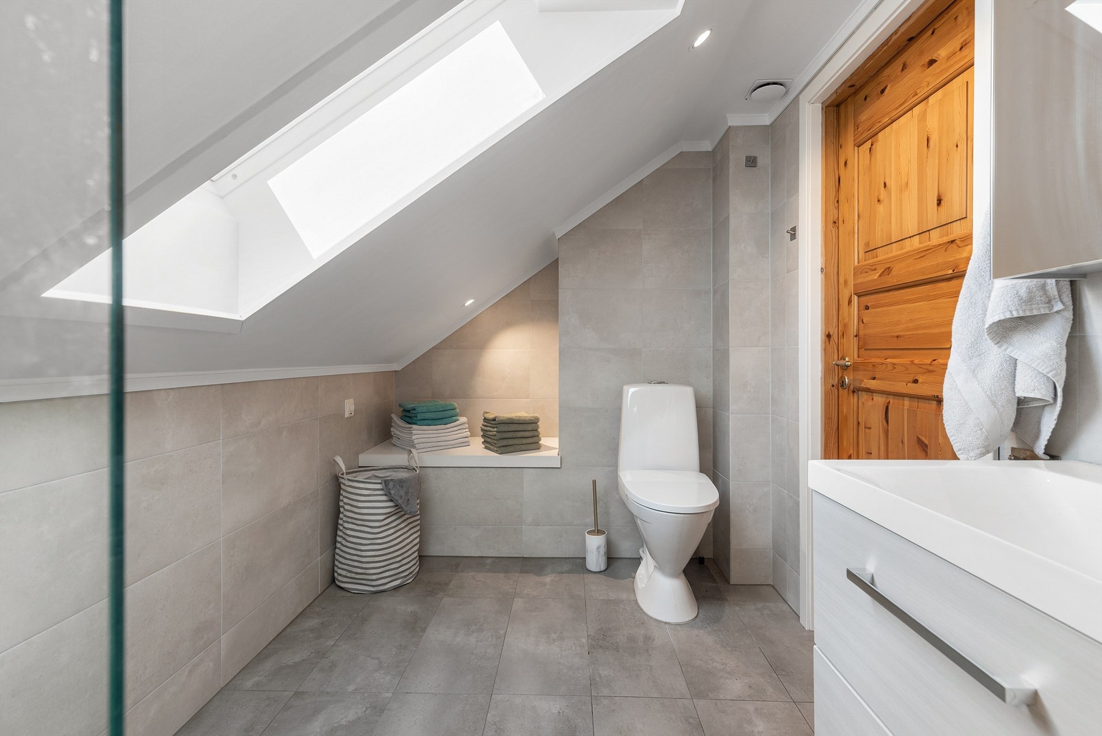 Badet har dusj i hjørne, downlights i tak og varmekabler i gulv Galleribilde