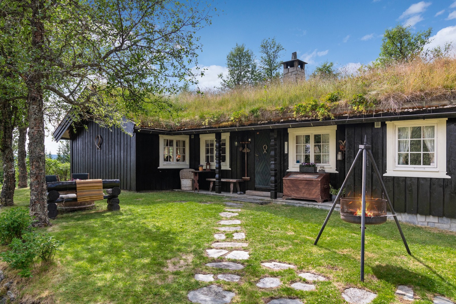 Pent opparbeidet tomt med dels plen, dels naturtomt. Steinlagt hellegang inn til overbygd inngangsparti. Galleribilde