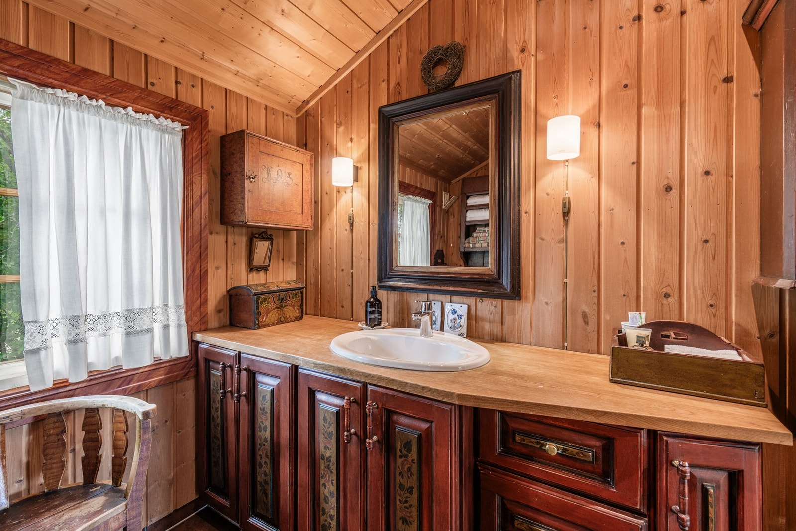 Badet har fliser på gulv, og trepanel på vegg. Galleribilde