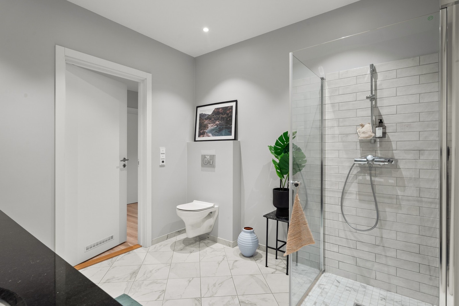 Romslig og delikat bad med nedsenket dusjhjørne i herdet glass, vegghengt toalett og behagelige varmekabler i gulv. Galleribilde