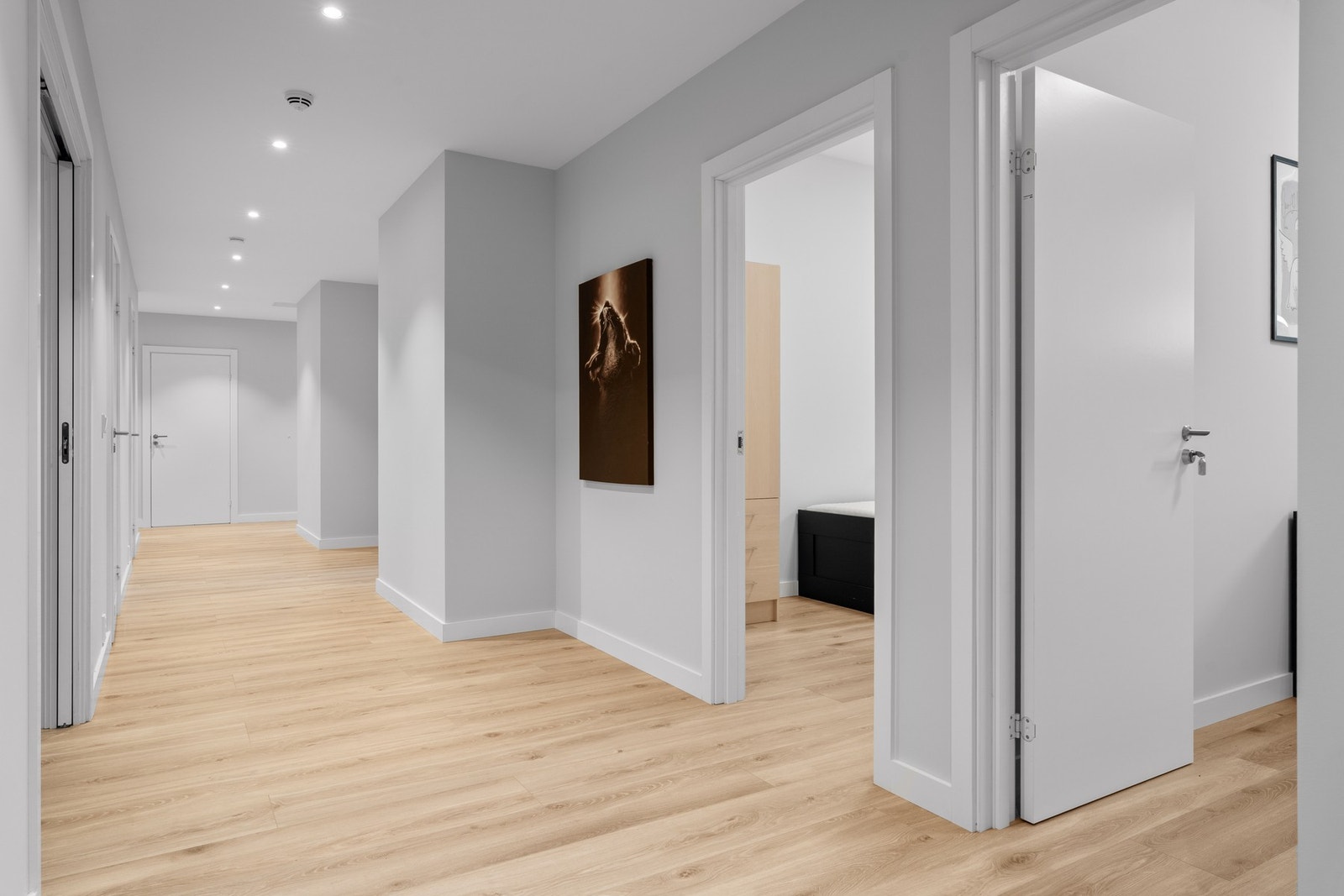 Praktisk og romslig gang som fungerer som et naturlig knutepunkt i boligen, med moderne belysning og enkel tilgang til rommene. Galleribilde