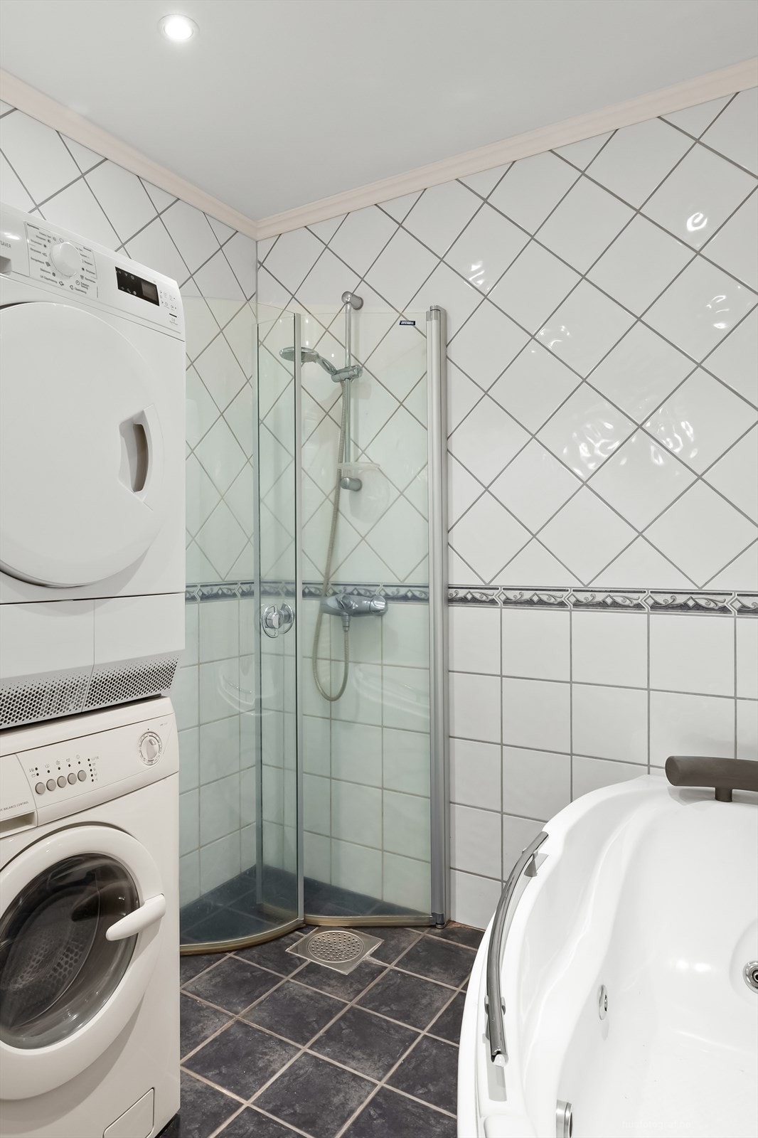 Badet har dusjhjørne med foldedører av glass og frittstående boblebadekar Galleribilde