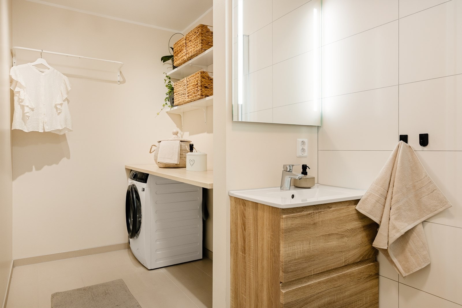 Badet er utstyrt med vegghengt toalett, helstøpt servant, skuffer under servant med slette fronter, dusjdører i klart glass og opplegg for vaskemaskin Galleribilde