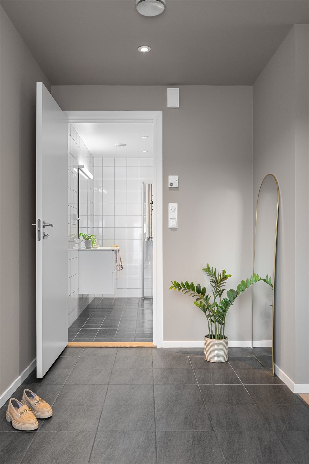 Rød tråd fra baderom til entré med fliselagt gulv med gulvvarme og downlights i tak. Galleribilde