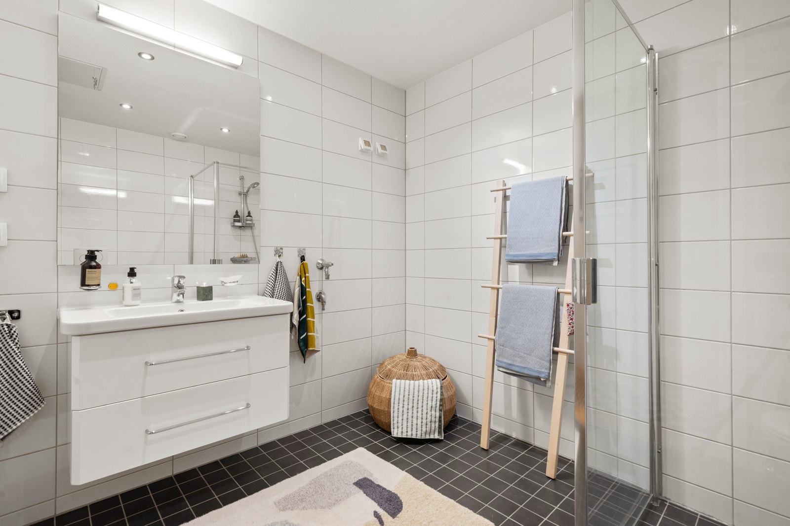 Delikat, flislagt bad med servantseksjon med skuffer og speil, kombinert med varmekabler i gulv som gir god komfort i hverdagen. Galleribilde