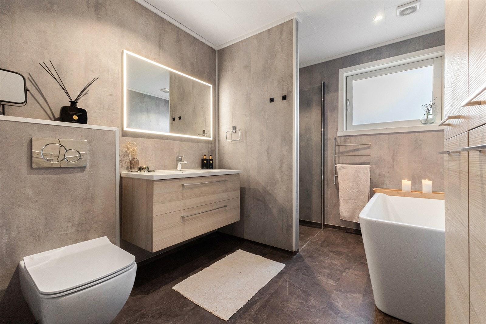 Badet ble totalrenovert i 2020. Her finner du innredning med skuffer, stort speil med integrert lys, vegghengt toalett, badekar og dusjnisje. Galleribilde