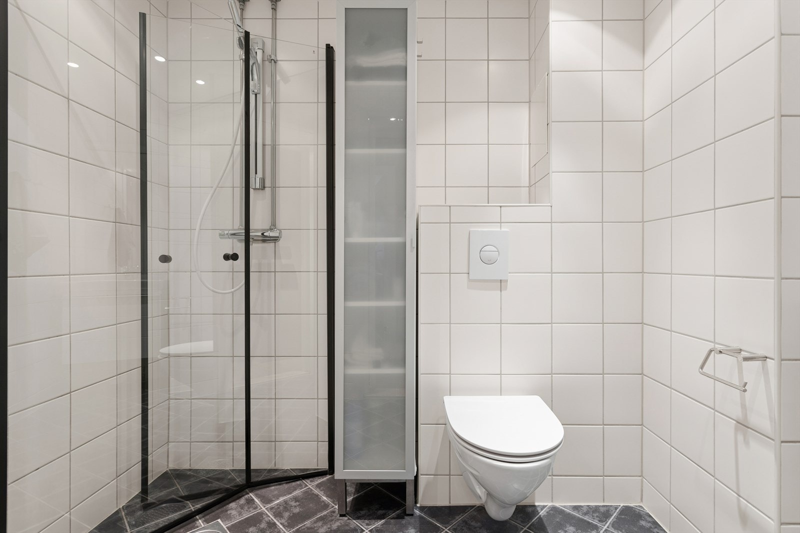 Rommet er utstyrt med veggmonterte dusjvegger, dusj direkte på gulv med termostat batteri, veggmontert klosett, servant med skuffer, speil, belysning og opplegg for vaskemaskin. Galleribilde