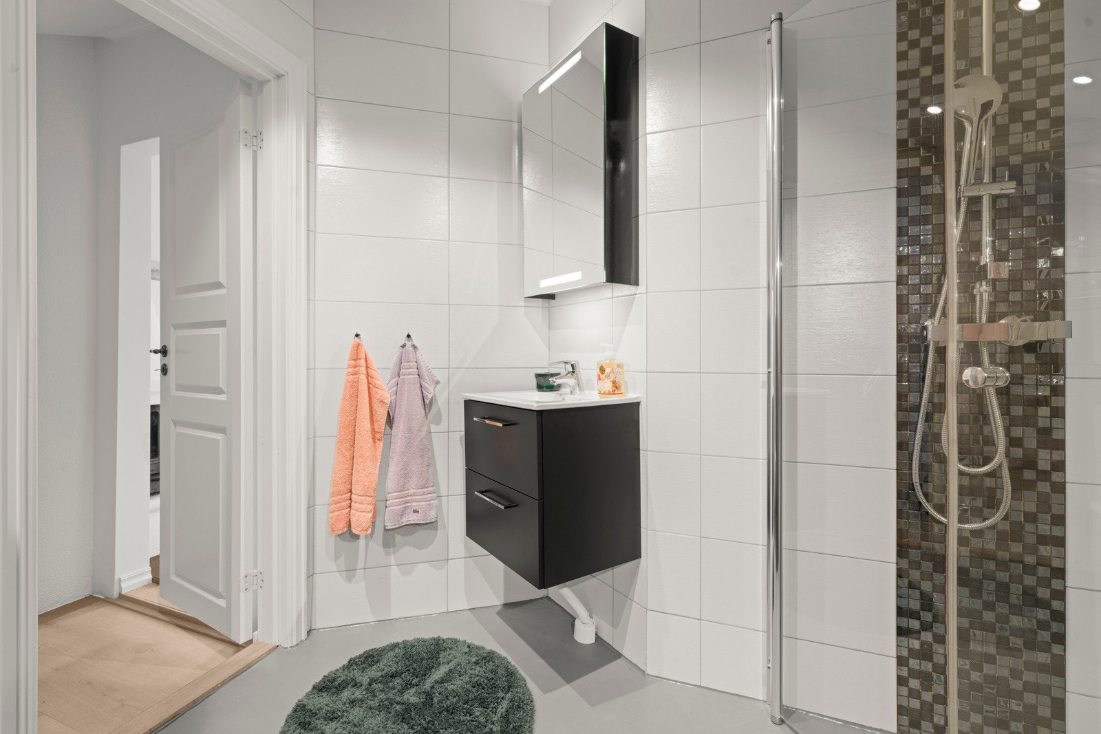 Rommet har innredning med nedfelt servant, veggmontert toalett, dusjvegger/hjørne. Galleribilde