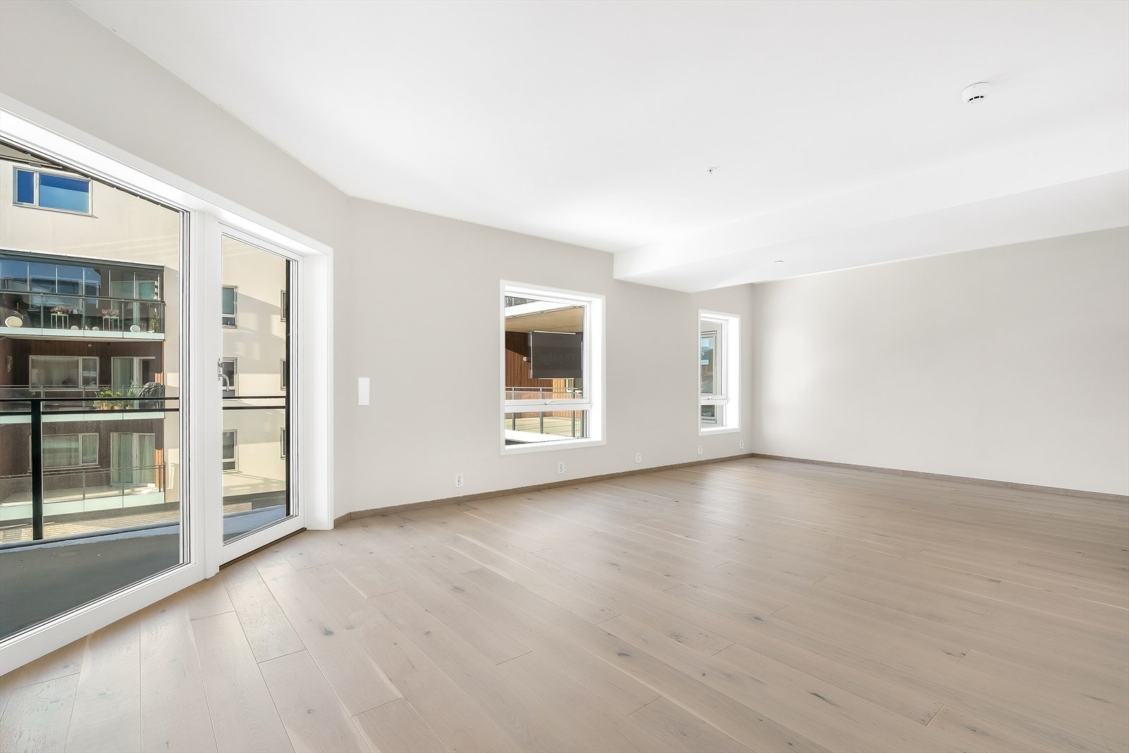 Stue med enstavs eikeparkett på gulvet og store vinduer som gir rikelig med naturlig lys. Galleribilde