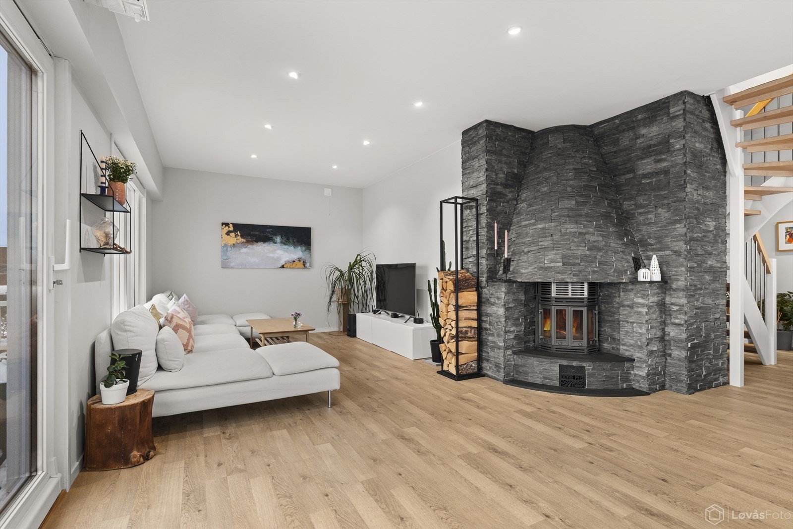 Stor og innbydende stue med god møbleringsfrihet, peis kledd i naturstein og moderne belysning. Galleribilde