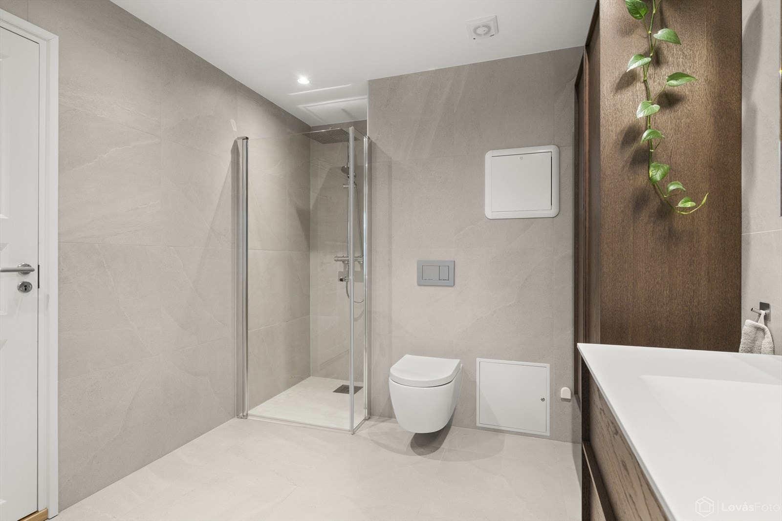 Romslig dusjsone med glassvegger, moderne slukløsning og vegghengt toalett. Galleribilde