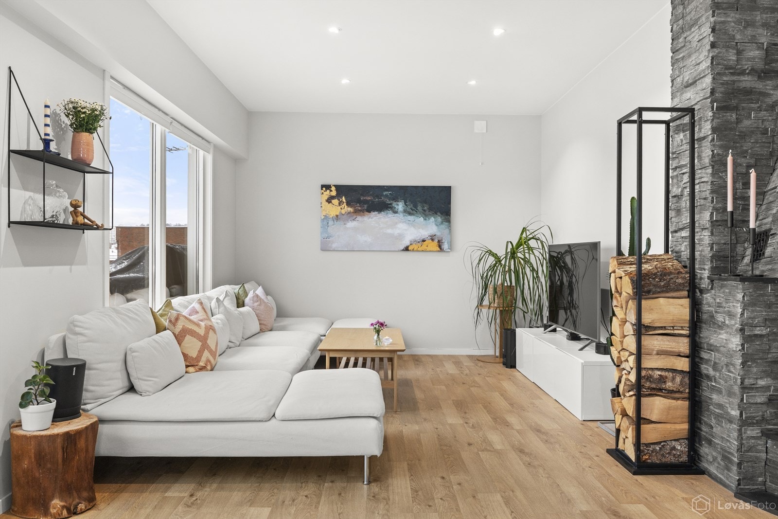 Oppholdsrommet fremstår som gjennomgående velholdt, med pene gulv, peis og god avstand mellom sittegruppe og mediesone. Galleribilde