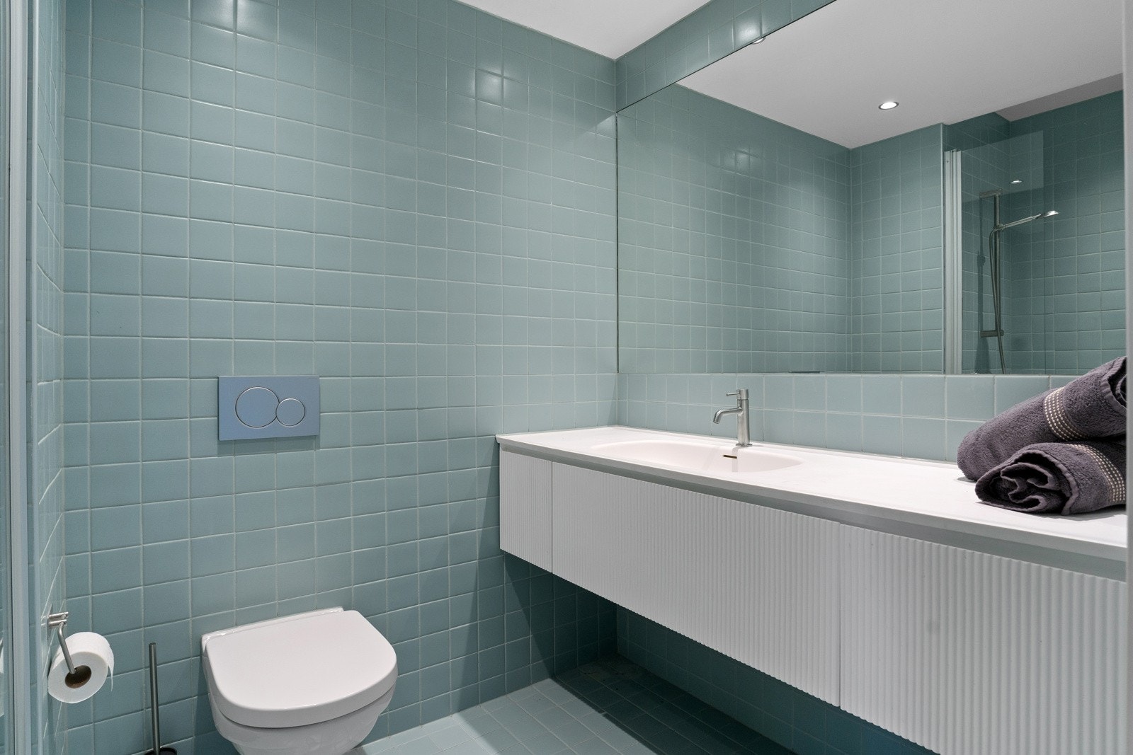 Pent flislagt baderom fra 2024 med varmekabler i gulv. Badet føles romslig, ettersom opplegg for vaskemaskin er plassert i gangen i plassbygde skap. Galleribilde