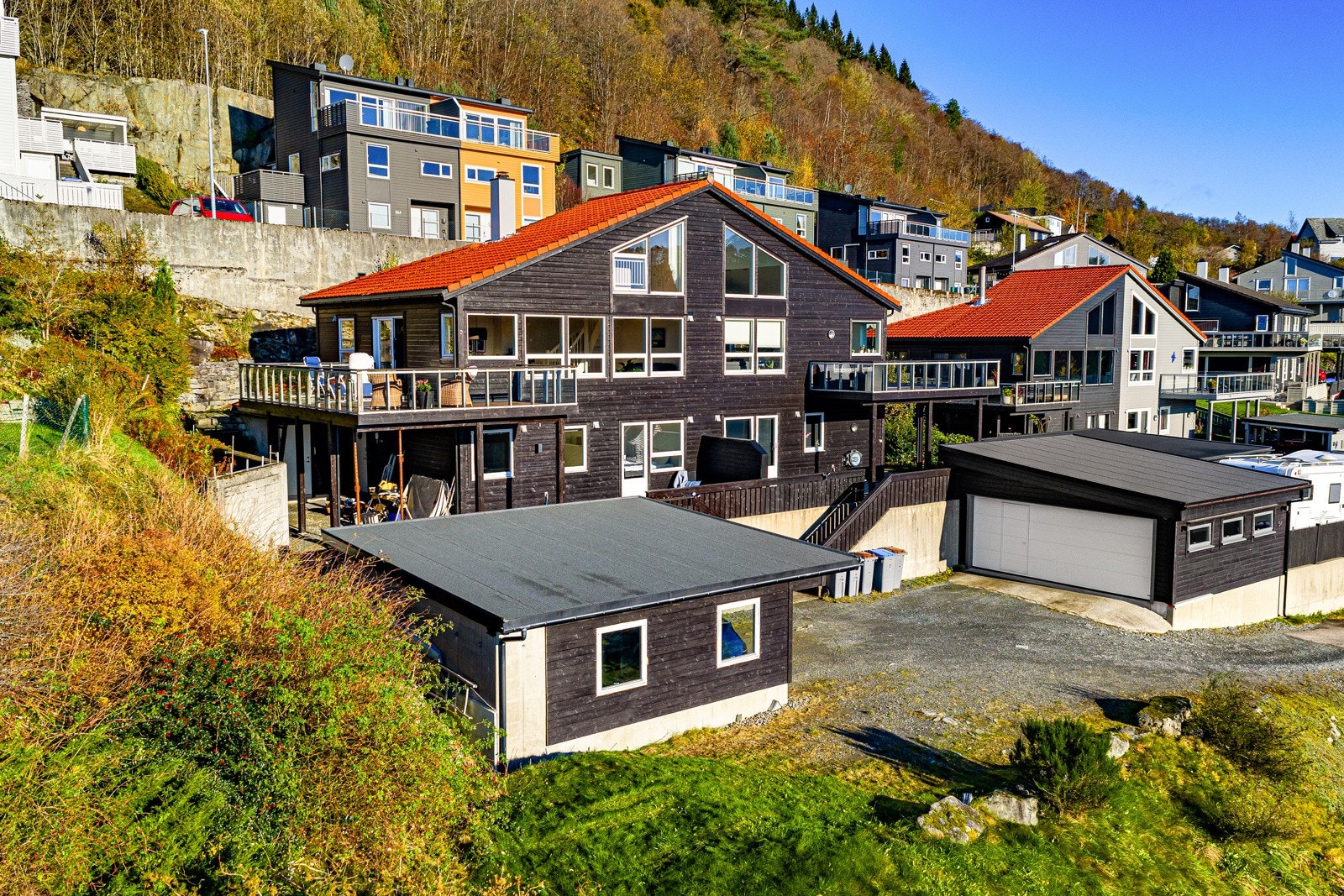 Husets fasade med gårdsplass og carport i front Galleribilde