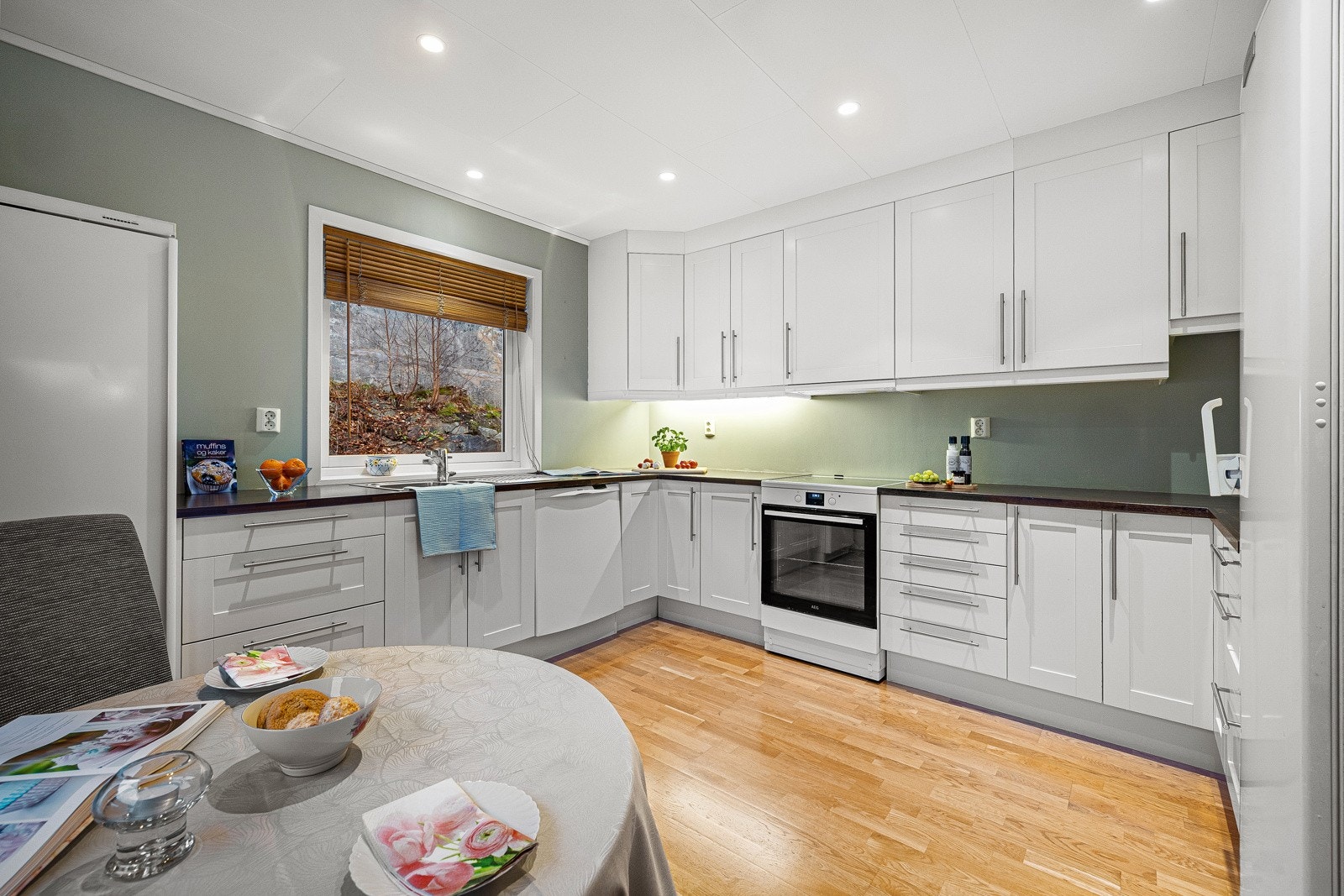 Kjøkkenet har hvite profilerte fronter med mørk laminat benkeplate Galleribilde