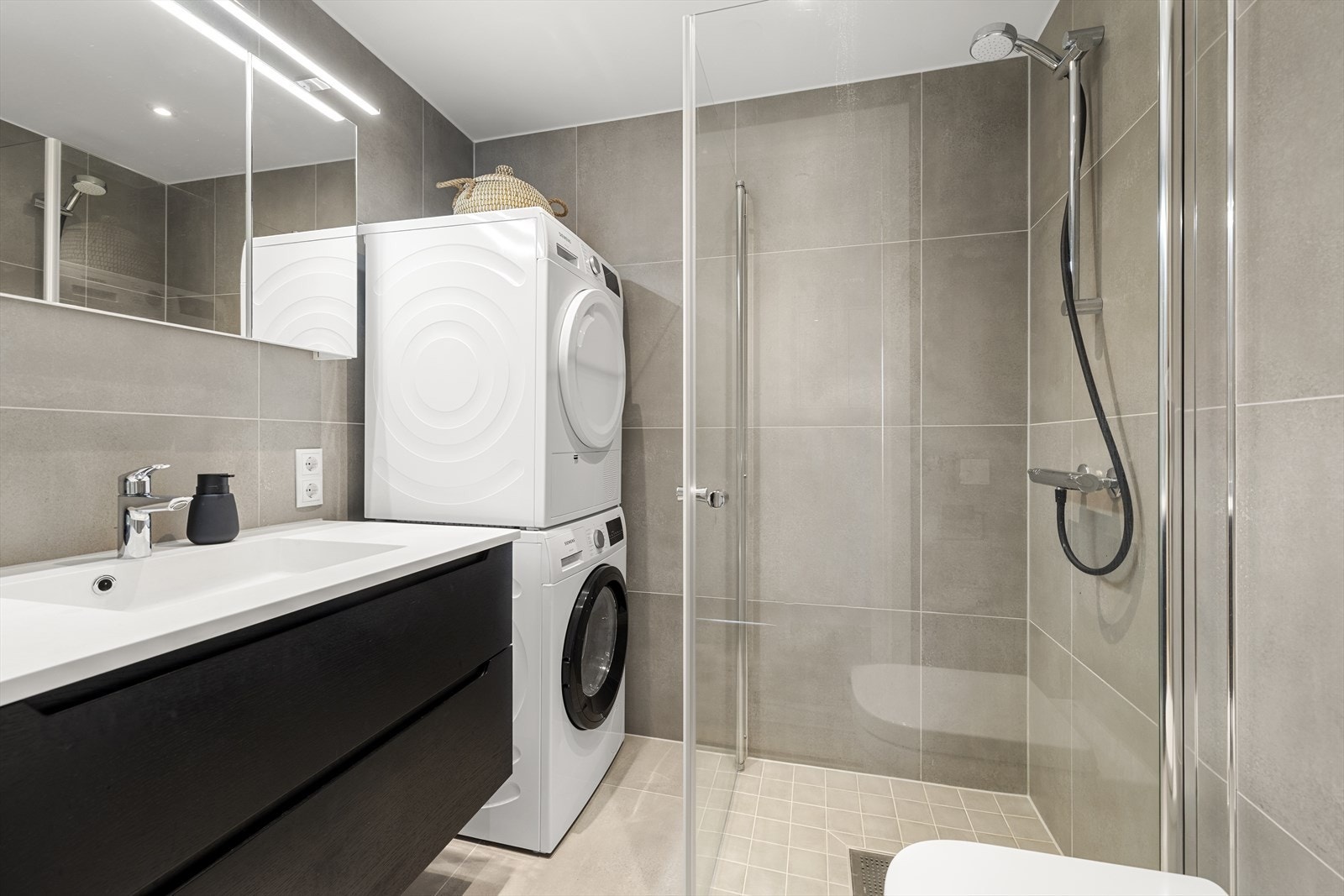 Badet er helfliset, har vannbåren gulvvarme, vegghengt toalett og opplegg for vaskemaskin og tørketrommel. Galleribilde