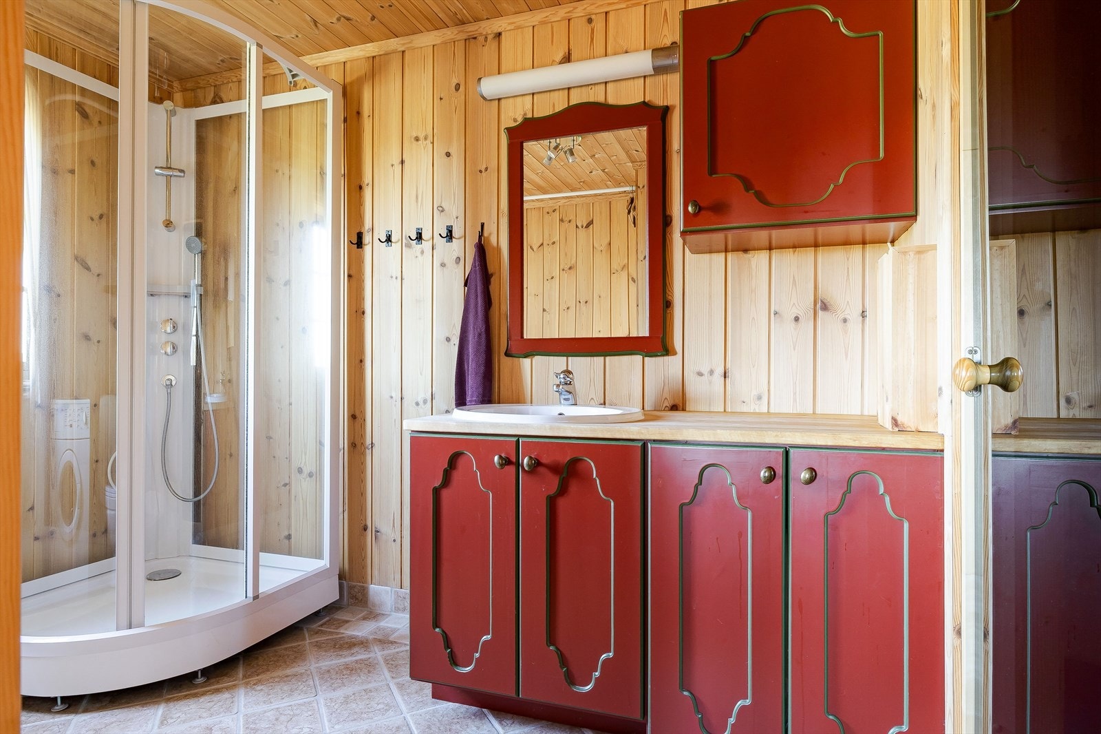 Baderom fra byggeåret innredet med servant på innredning, speil med belysning og overskap, dusjkabinett, toalett og opplegg for vaskemaskin. Galleribilde