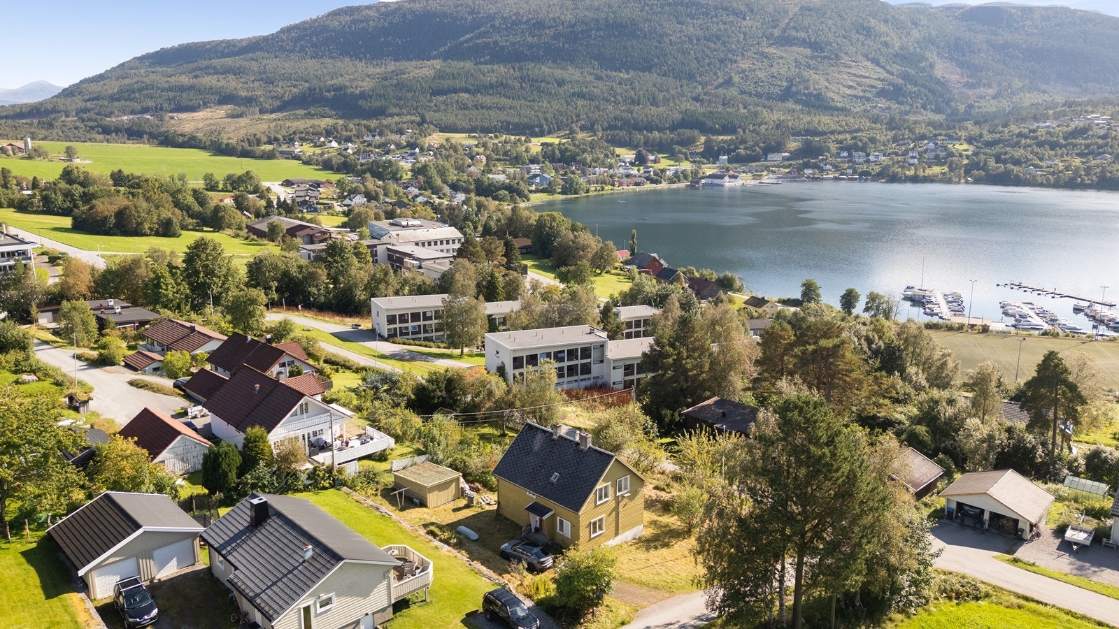 Dronebilde over nærområdet viser boligens strategiske beliggenhet nær Tingvollfjorden, med kort avstand til sentrum og lokale fasiliteter. Galleribilde