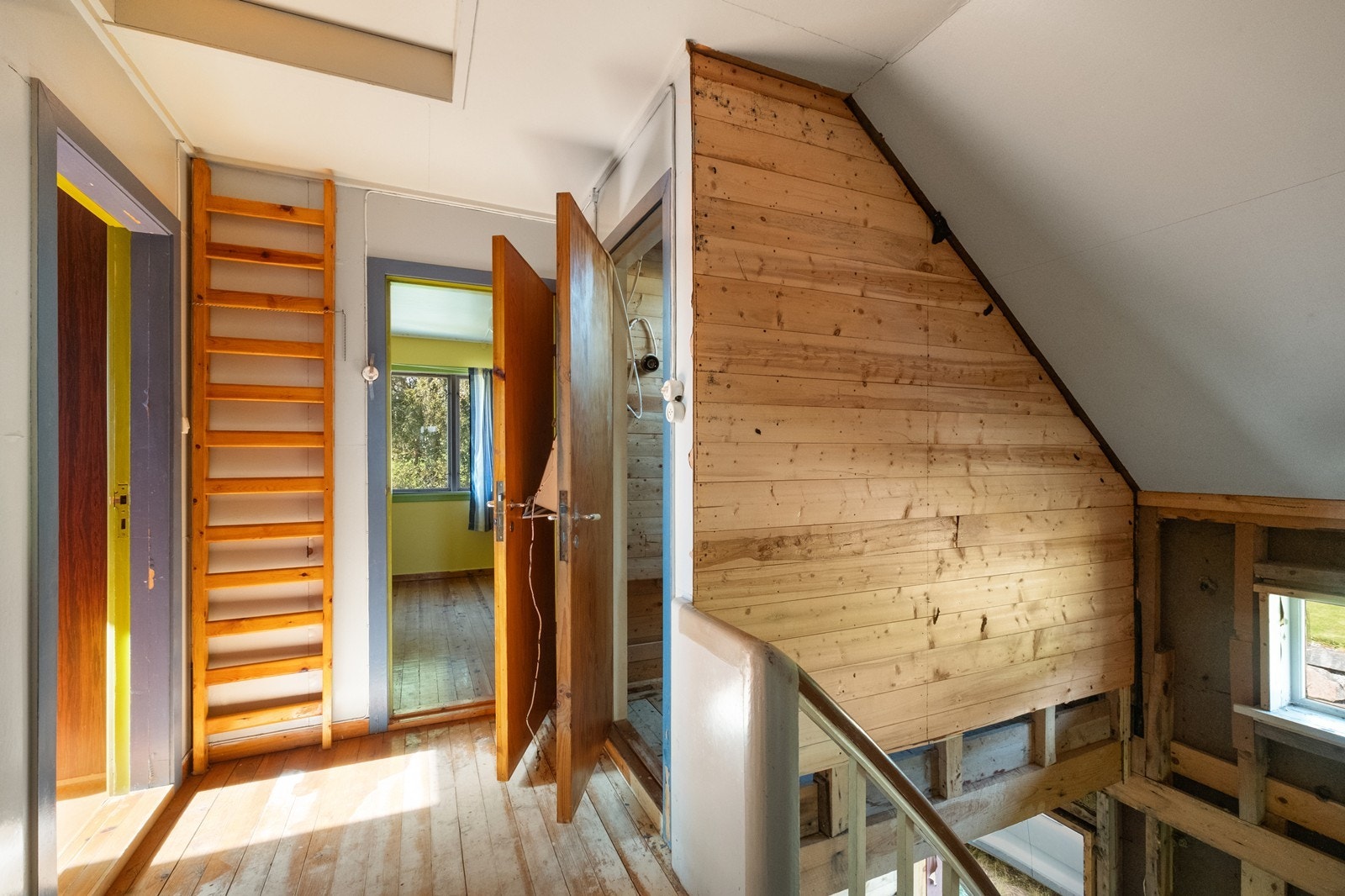 Lyst gangområde med furugulv og åpen konstruksjon i veggene gir mulighet for tilpasning og renovering. Galleribilde