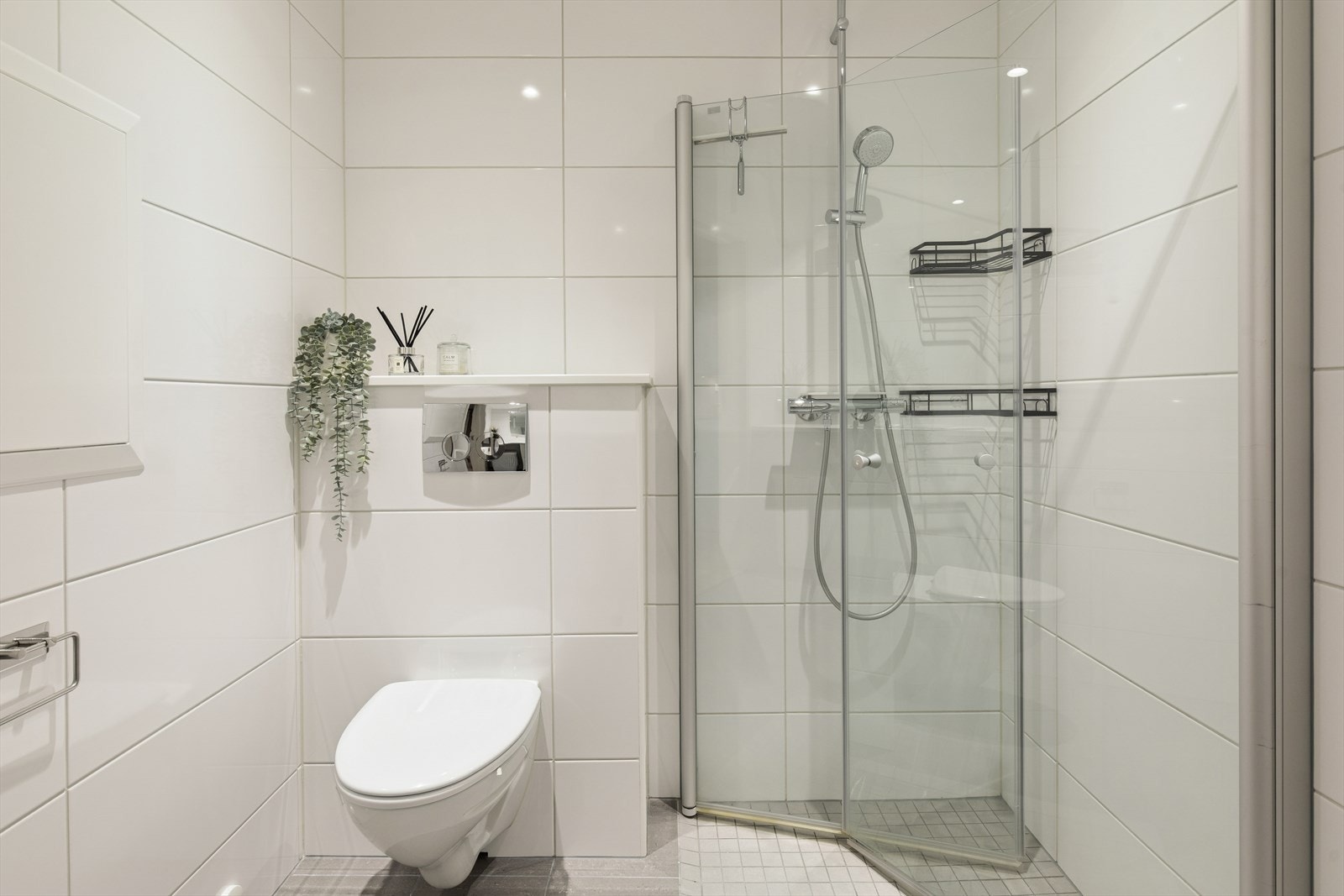 Baderommet er innredet med moderne baderomsmøbler, nedfelt servant, veggmontert toalett og et dusjhjørne med to svingbare glassdører som gir en stilren og praktisk løsning. Galleribilde